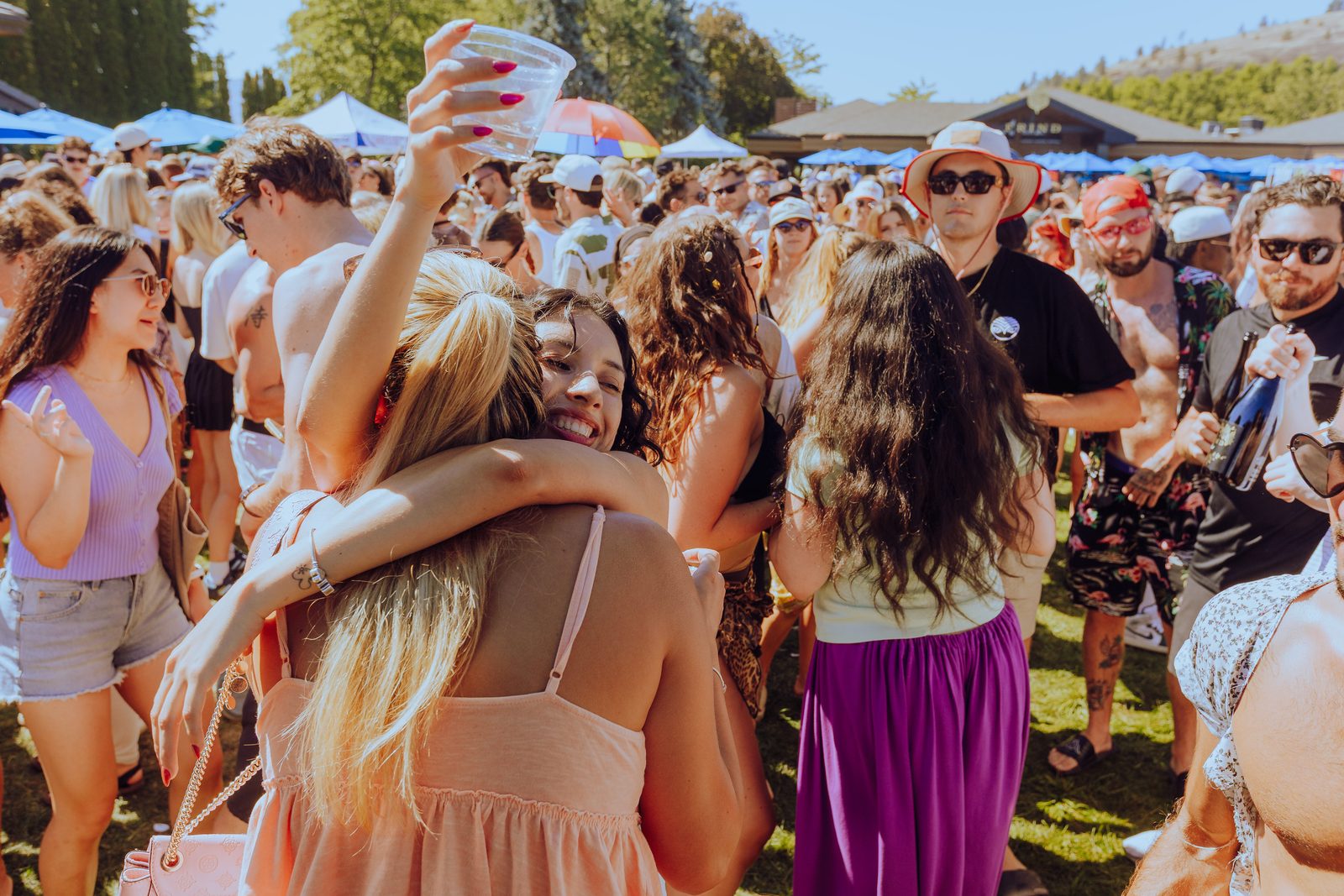 Two friends hugging in a golden sunlit crowd
