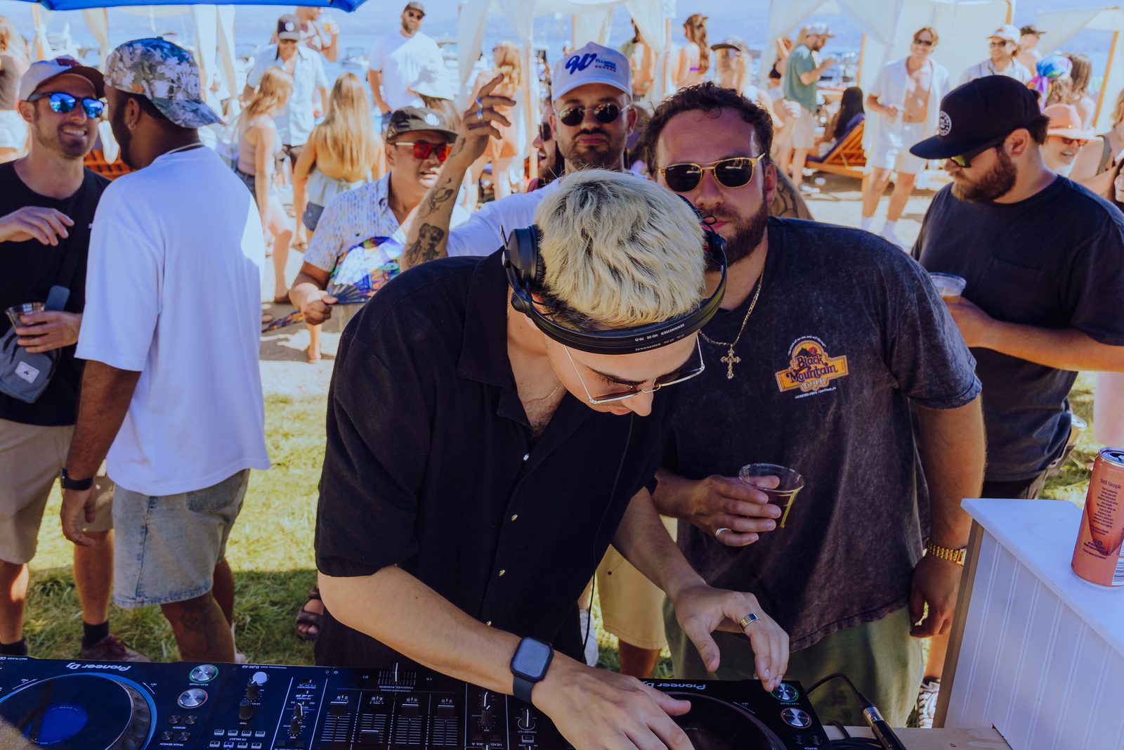A DJ mixing with a lively crowd behind