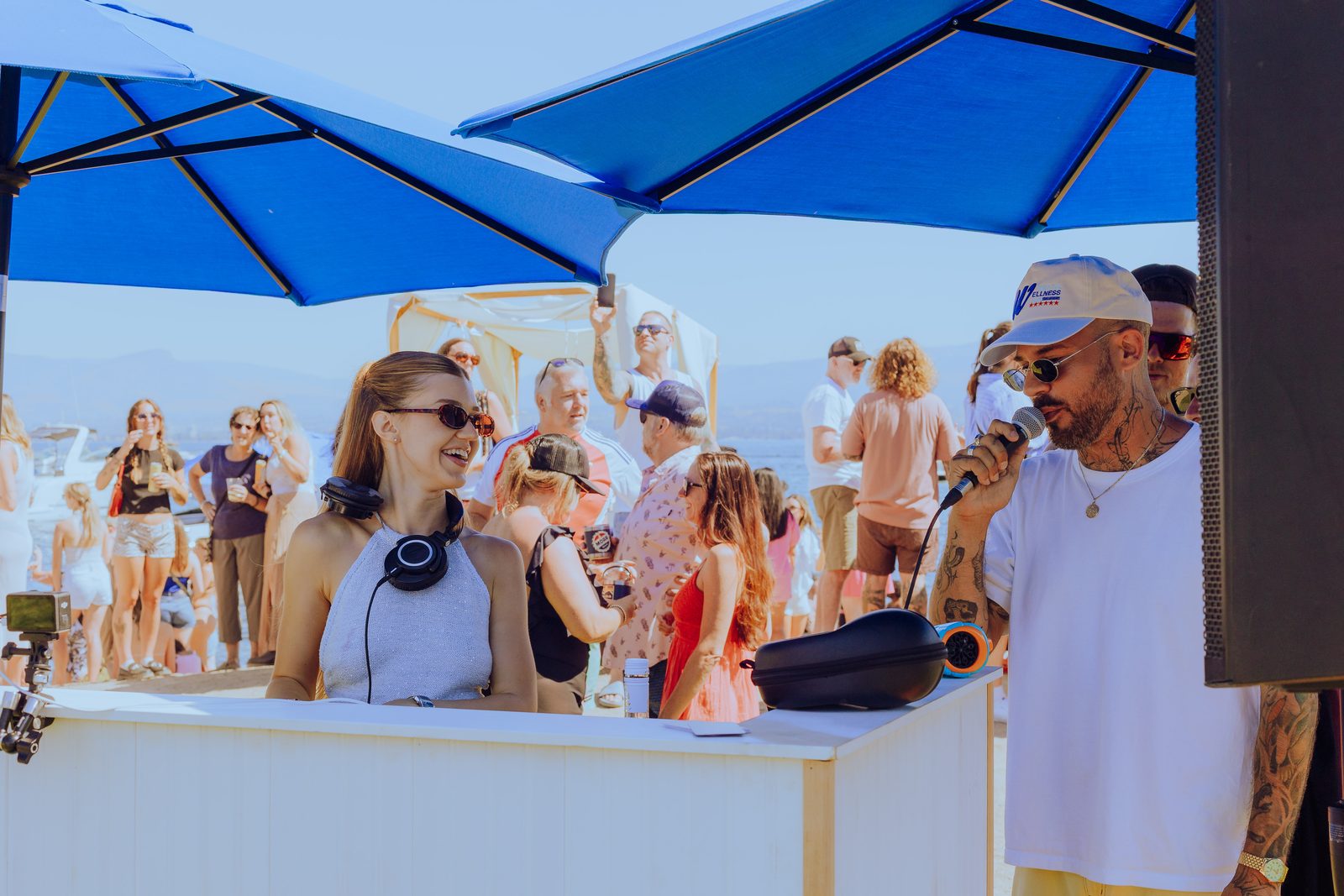 A DJ on the mic under a blue umbrella